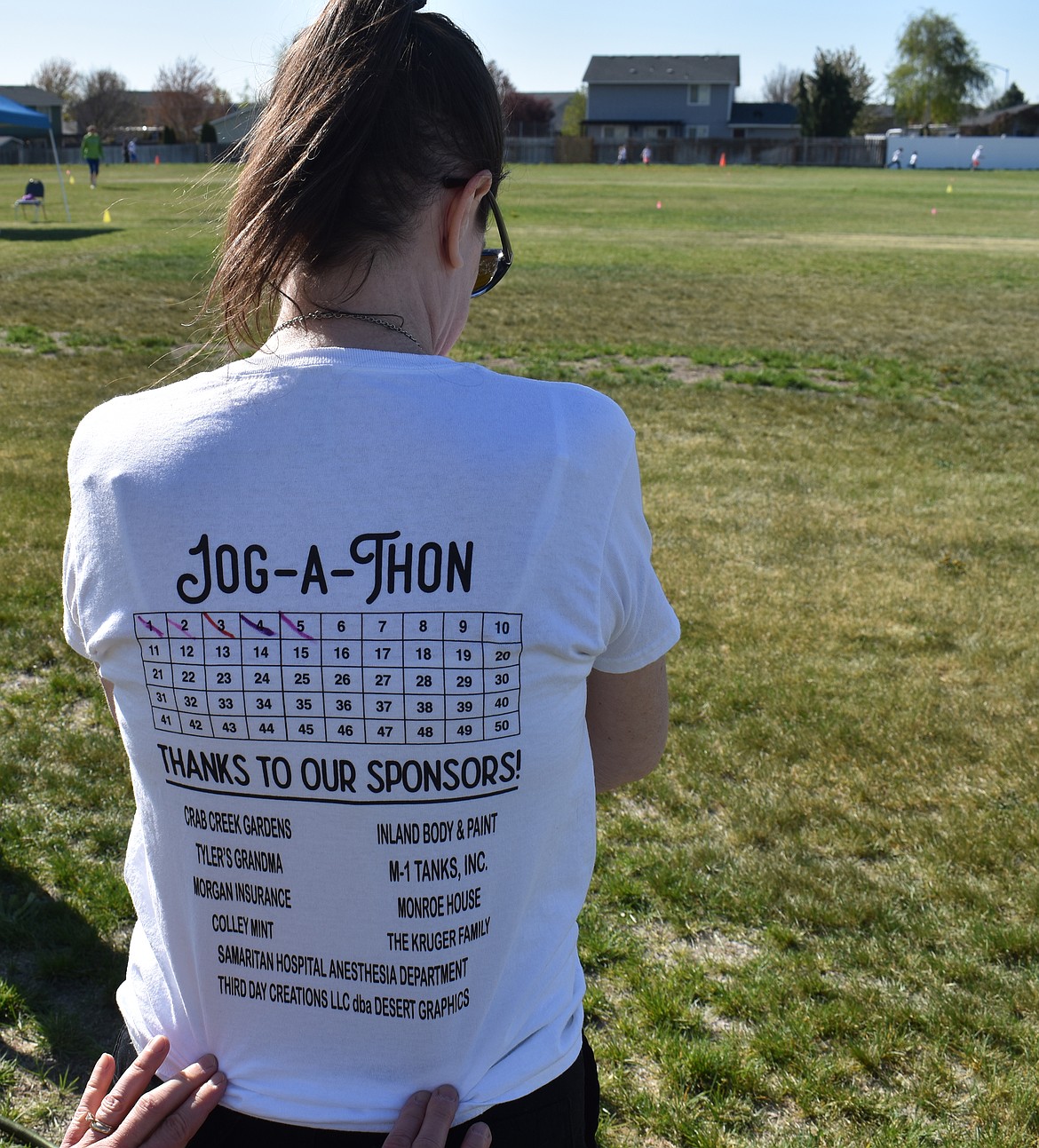 Crestview Christian School teacher Jenna Woodcook shows her custom-printed T-shirt for marking off laps at the Jog-a-Thon. She had only completed five quarter-mile laps, but some of the students would go on to complete 20 or more, she said.