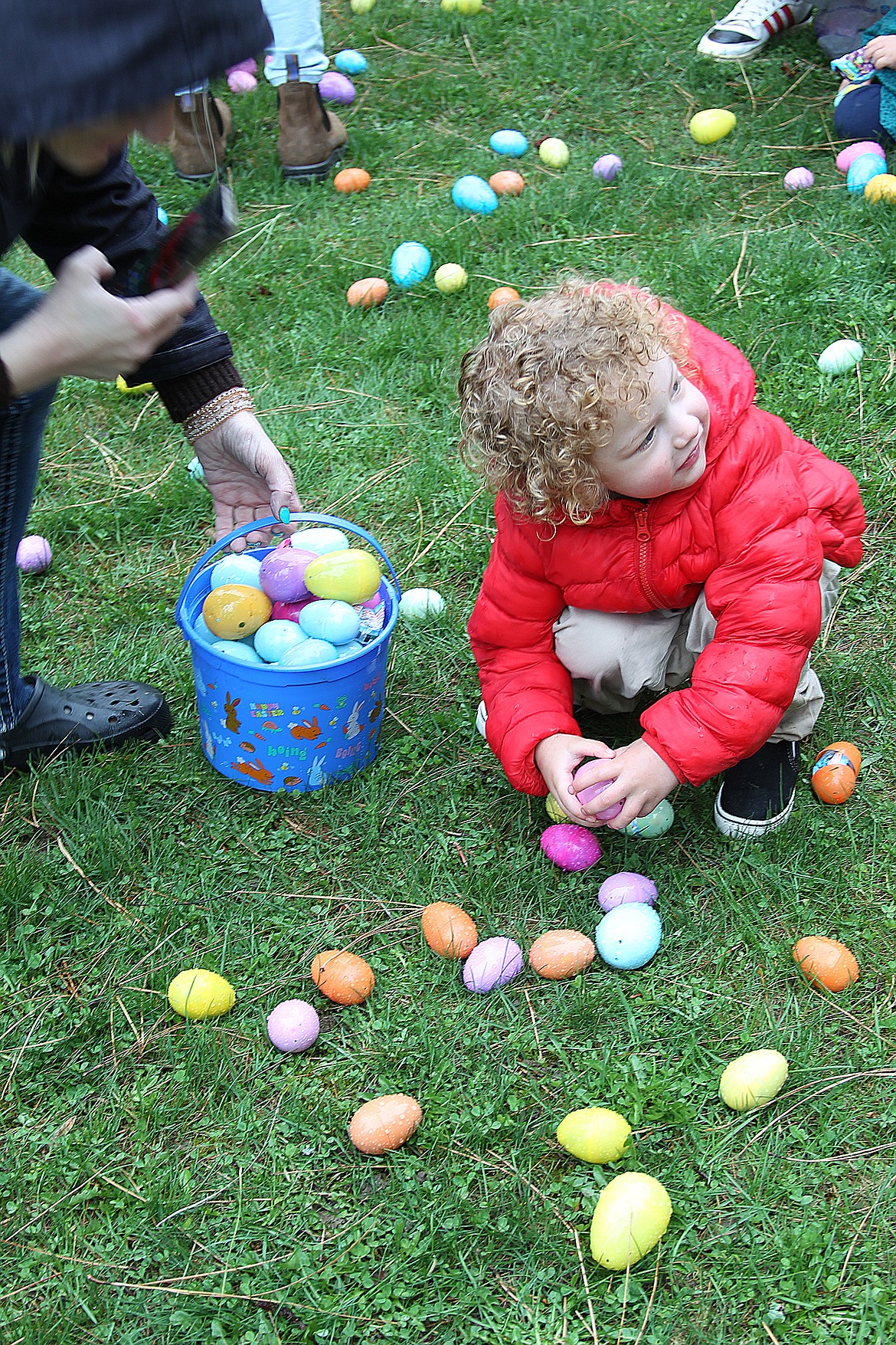 A youngster looks up and smiles as he sits surrounded by a few of the 10,000 candy-filled Easter egg hunts scattered throughout Lakeview Park during the Sandpoint Lions' annual Easter egg hunt Saturday.