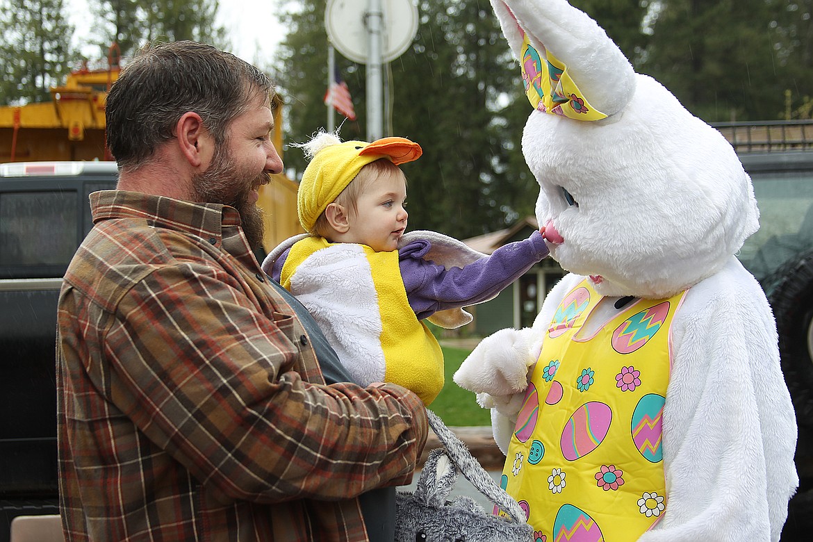 Ellie Mangus, with a helping hand from dad Ethan, reaches out to pat the Easter Bunny on the nose during the Sandpoint Lions' annual Easter egg hunt Saturday.