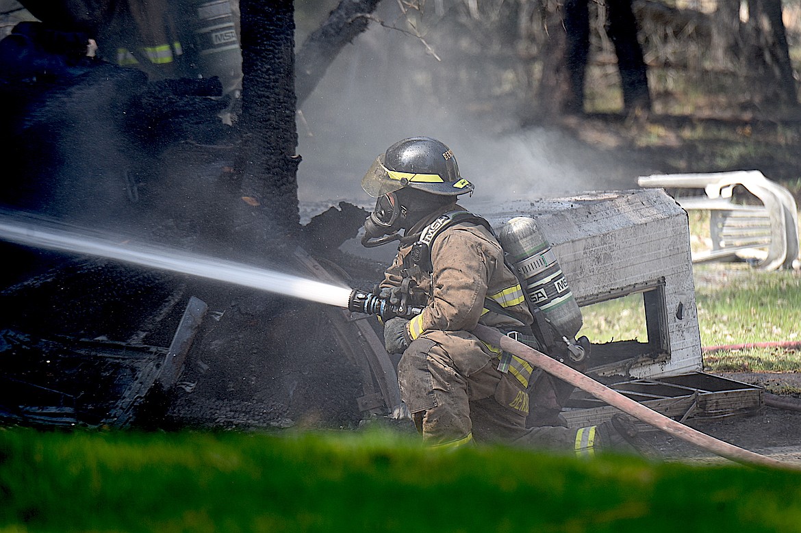 Libby Volunteer Fire Department firefighter Neil Benson sprays water on a carport that was severely damaged in a fire Wednesday, April 23, 2025, at a residence on Cherry Creek Drive, south of Libby. (Scott Shindledecker/The Western News)