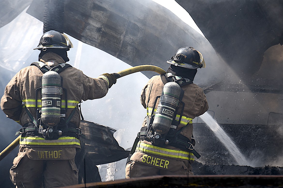 Libby Volunteer Fire Department firefighters Steve Scheer and Eric Uithof spray water on a carport that was severely damaged in a fire Wednesday, April 23, 2025, at a residence on Cherry Creek Drive, south of Libby. (Scott Shindledecker/The Western News)