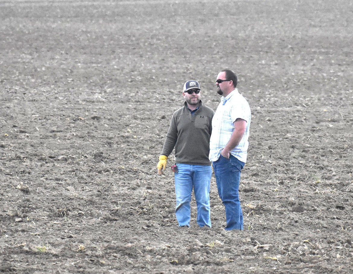 Grant Morris, right, talks with an employee in a field at Schneider Farms. Morris came to Schneider Farms 20 years ago right out of college and is now co-owner.