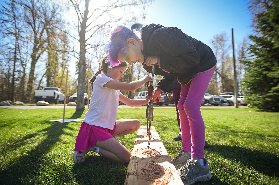 Edgerton Elementary third-graders use a pair of braces with bits attached to drill holes at the Flathead High School wood shop station at the Arbor Day celebration at Lawrence Park on Friday, April 25. (Casey Kreider/Daily Inter Lake)
