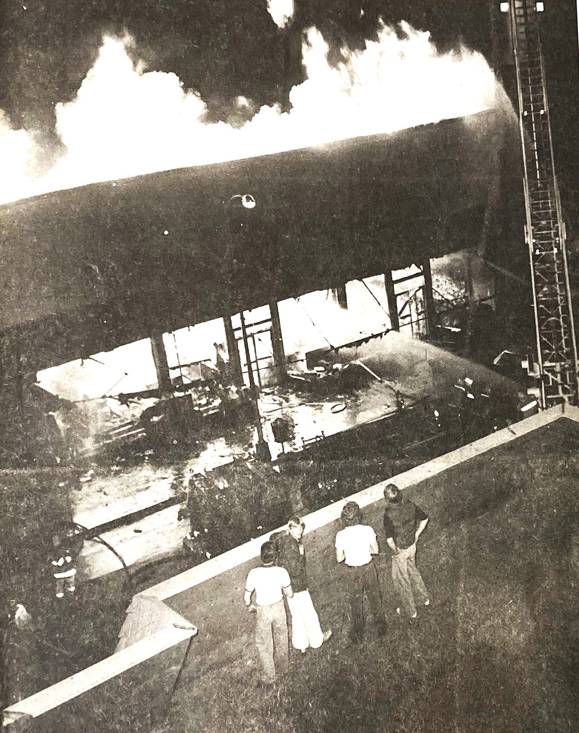 Spectators on a rooftop watch firemen battle the Woolworth fire April 26, 1980.