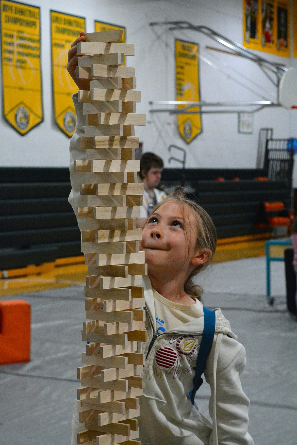 Lacy reaches up, up, up to add onto her impressive tower during the Family Science night last week at St. Regis School. (Mineral Independent/Amy Quinlivan)