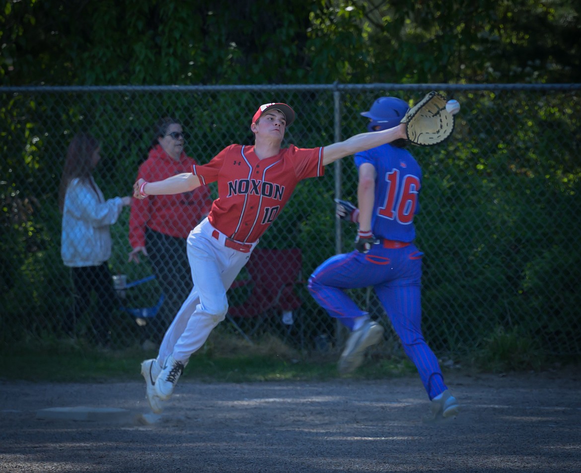 Noxon's Ian Brown (red jersey) stretches to receive a throw at first during Red Devils 5-4 win over Bigfork this past week in Noxon. (Tracy Scott, Valley Press)