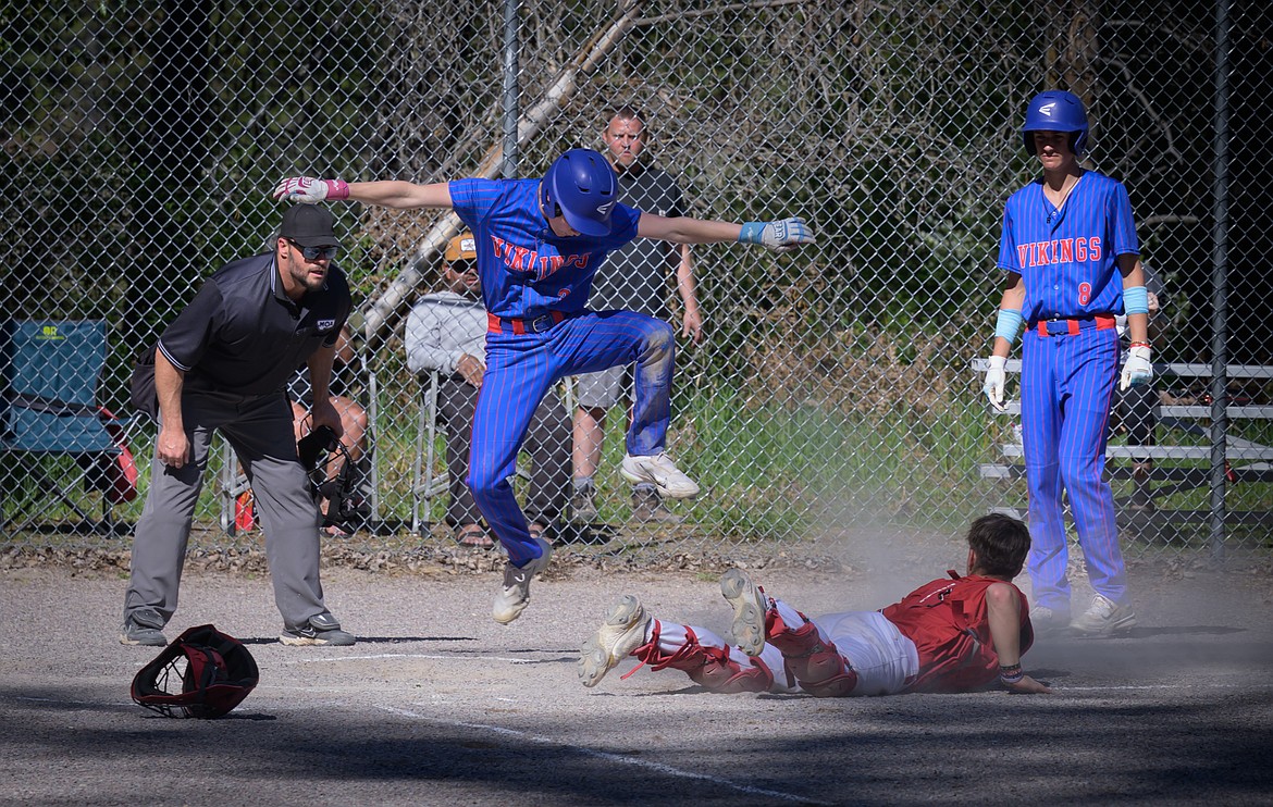 Noxon catcher Justice Kayser (red jersey) is prone after tagging Bigfork's Brady Campbell (hopping) out at home during their game this past week in Noxon. (Tracy Scott, Valley Press).