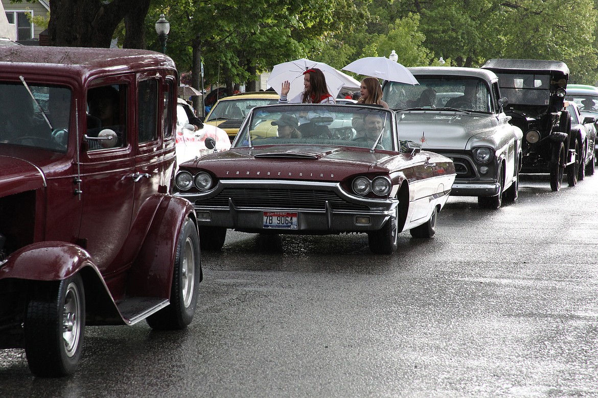 Young classic car participants use an umbrella to keep them dry as they take part in the annual Lost in the '50s classic car cruise on Friday.