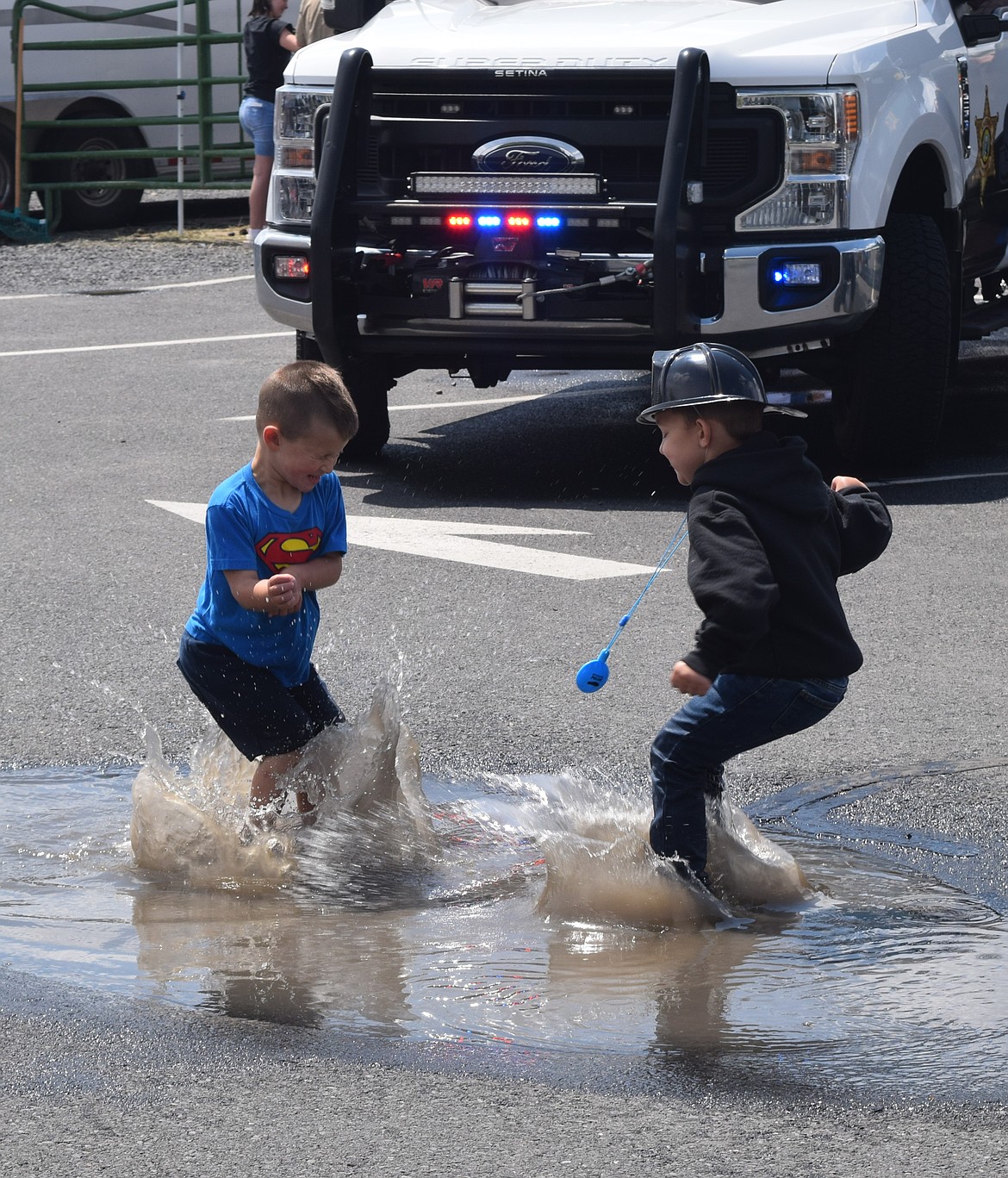 Jax, left and Beau, right, jump in puddles during the Touch a Truck event Saturday. The event started off with a downpour in the morning, but the children made the best of it.