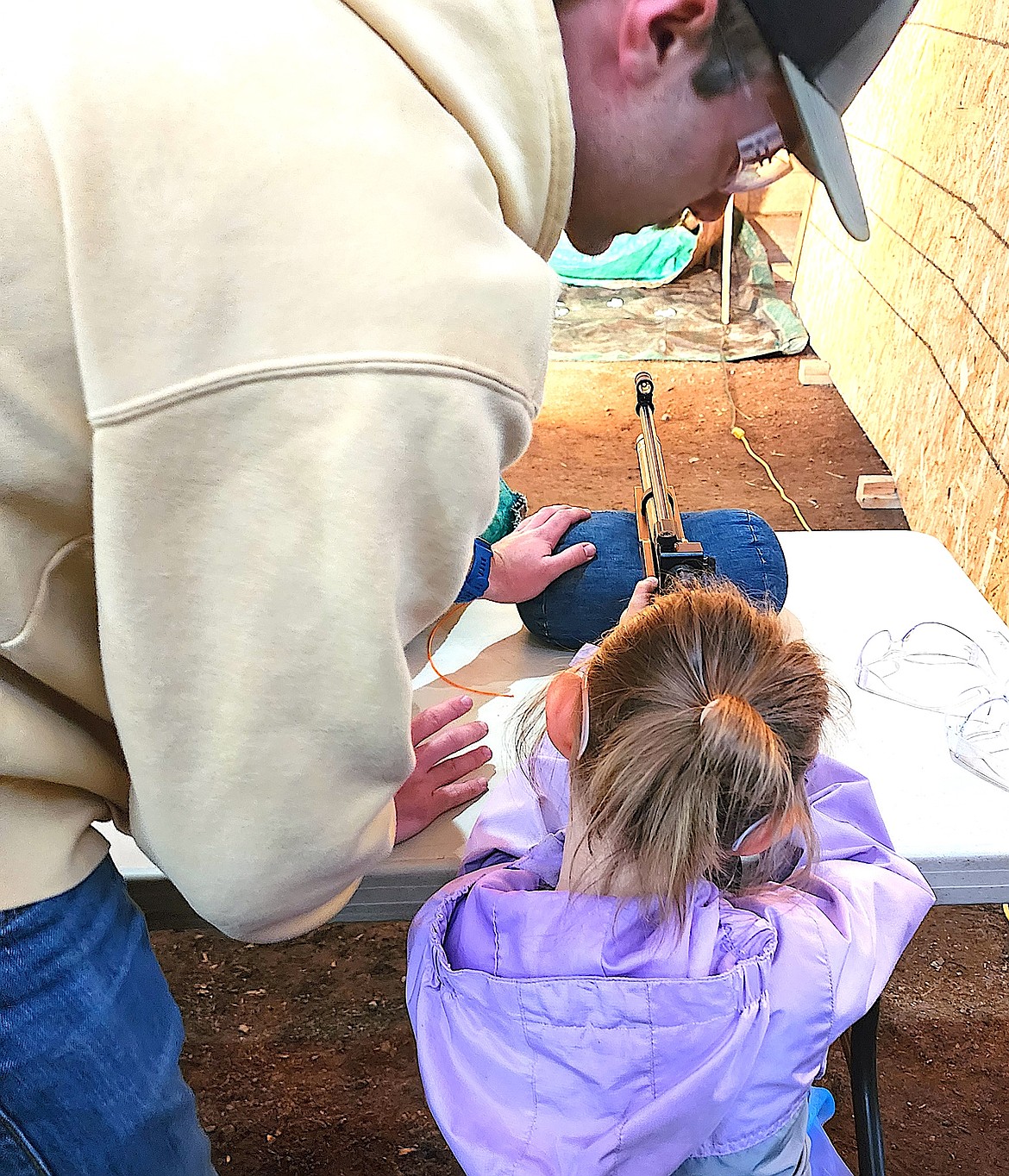Colter Cornwell shows Riley Taylor how to hold her air rifle as she aims at small wooden sheep. (Berl Tiskus/Leader)
