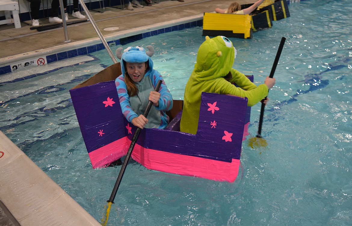 A team styled after the movie "Monsters Inc." paddles to complete a lap in the pool during their cardboard boat race.