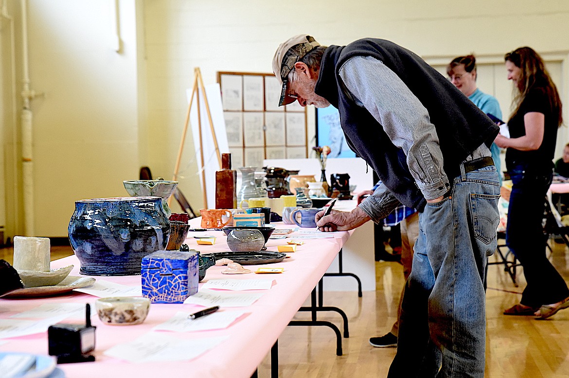 An admirer of a piece of pottery makes a bid during the silent auction at the Troy High School's annual student art show Tuesday, May 20, 2025. (Scott Shindledecker/The Western News)