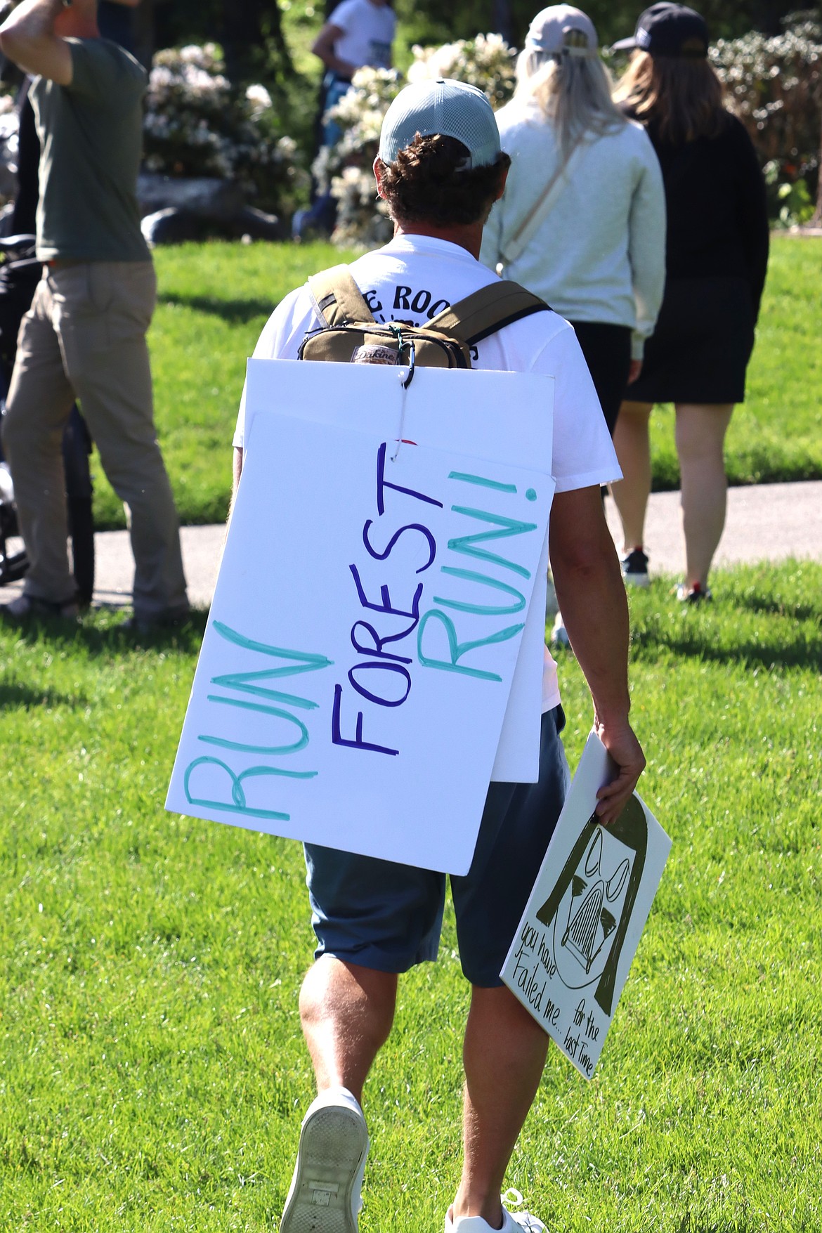 A spectator carries signs at the Coeur d'Alene Marathon on Sunday.