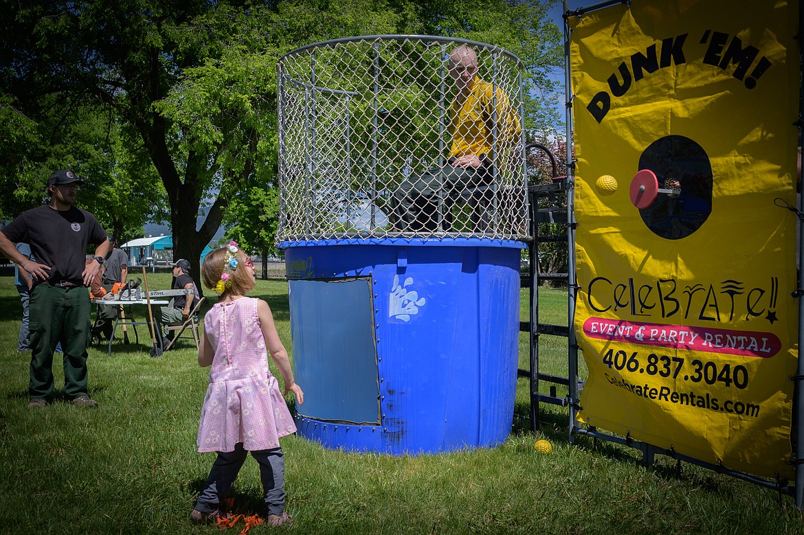 Maggie Boon, 6, hits the bullseye and dunks DNRC firefighter Conner Mathews. (Tracy Scott/Valley Press)
