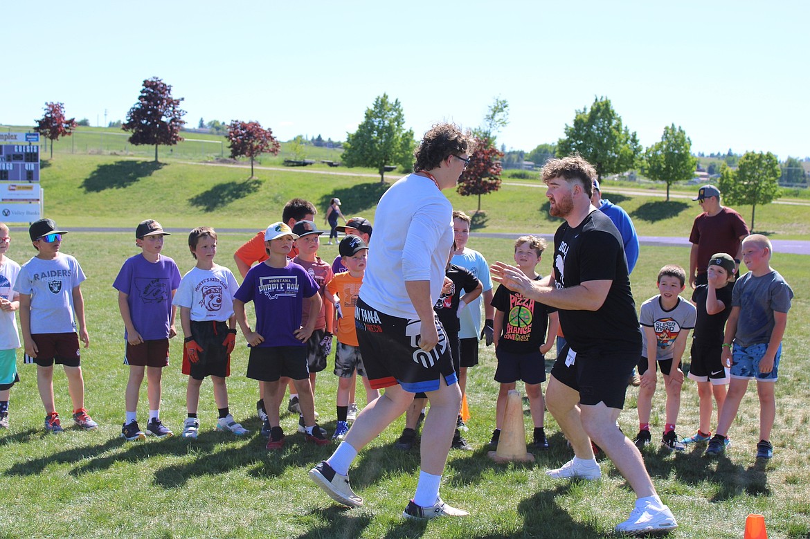 Polson Junior Brody Bulette and Polson alum and University of Montana Grizzly Braunson Henriksen show a drill to campers. (Kaleb Unger/Leader)
