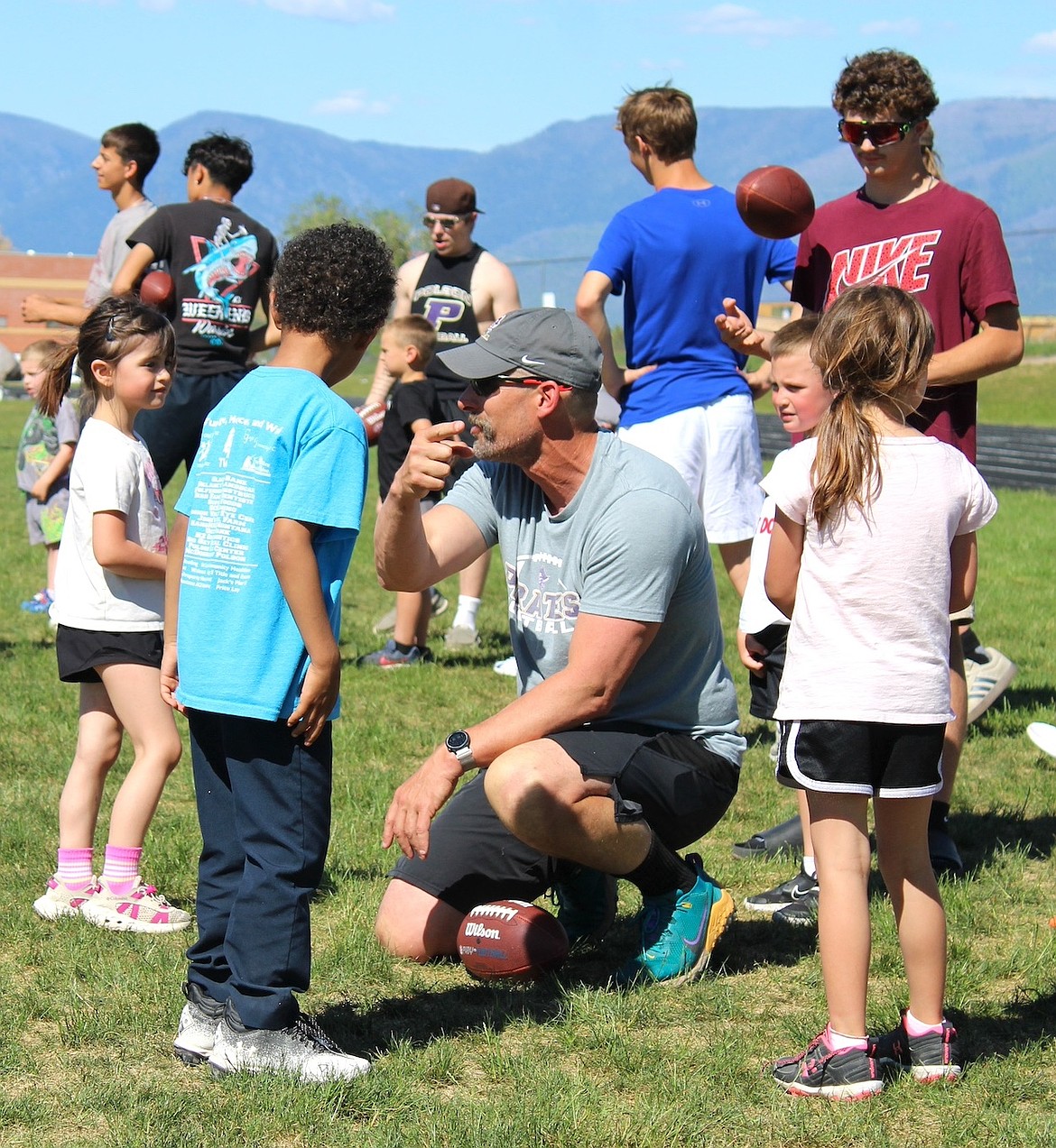Polson coach Ira Brown gets on the level of campers to describe a drill. (Kaleb Unger/Leader)