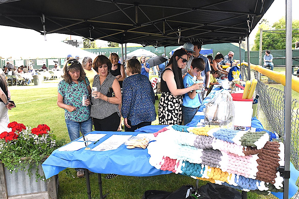Attendees of the Libby Loggers Dinner on the Diamond event Friday, June 6, 2025, examine some items in the silent auction at Lee Gehring Field. (Scott Shindledecker/The Western News)