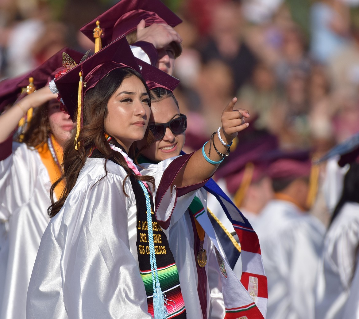 Several 2025 Moses Lake High School graduates point and look for their parents and friends in the crowd Tuesday.