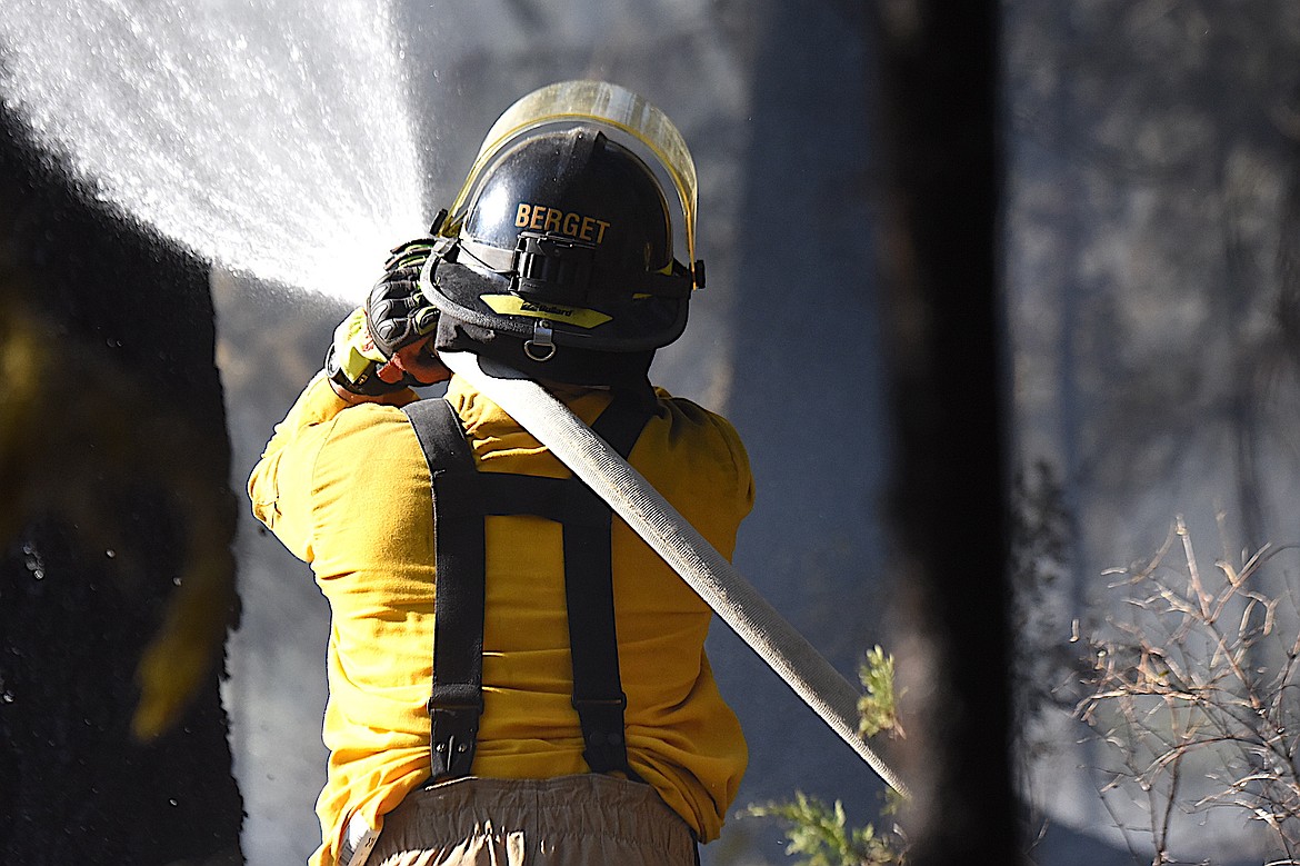 Libby Volunteer Fire Department Charlie Berget sprays water on a wild land fire Monday, June 9, 2025, on a small strip of land between Montana 37 and the Kootenai River just below the Dunn Creek Flats Campground. (Scott Shindledecker/The Western News)