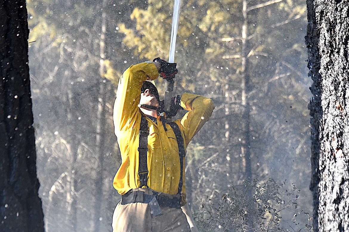 A Libby Volunteer Fire Department member sprays water on a wild land fire Monday, June 9, 2025, on a small strip of land between Montana 37 and the Kootenai River just below the Dunn Creek Flats Campground. (Scott Shindledecker/The Western News)