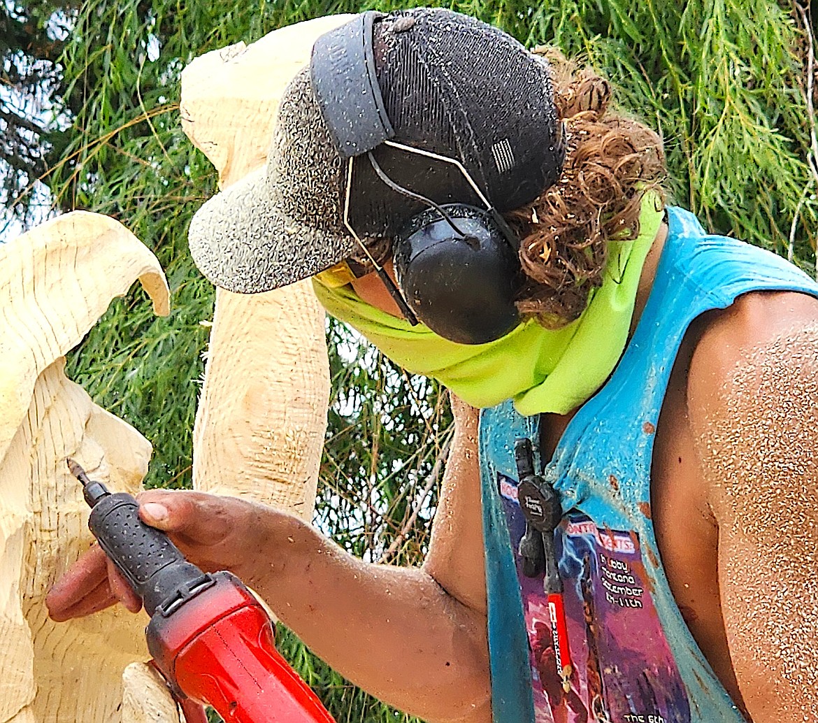Sprinkled with sawdust, chainsaw carver Hayden Wright does some close-up work on his shaman's face. (Berl Tiskus/Leader)