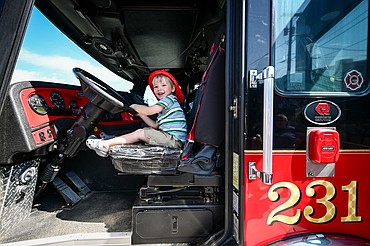 Beau Reynolds, 2, sits in the driver's seat of Whitefish Fire Department's engine 231 during a Touch a Truck fundraising event for the Whitefish 9/11 Memorial outside Black Rifle Coffee Company in Kalispell on Saturday, June 14. (Casey Kreider/Daily Inter Lake)