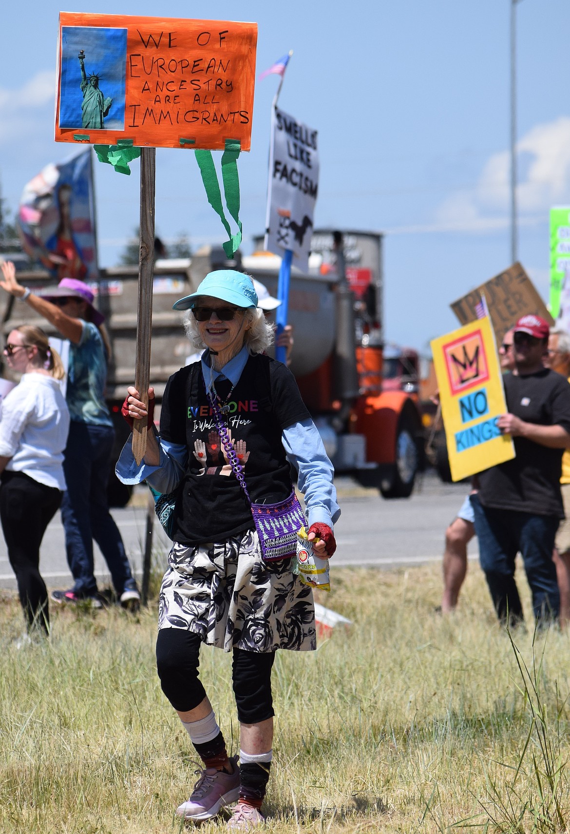Gina Brooks of Coeur d'Alene smiles as she holds a sign among other "No Kings" protestors in Coeur d'Alene on Saturday.