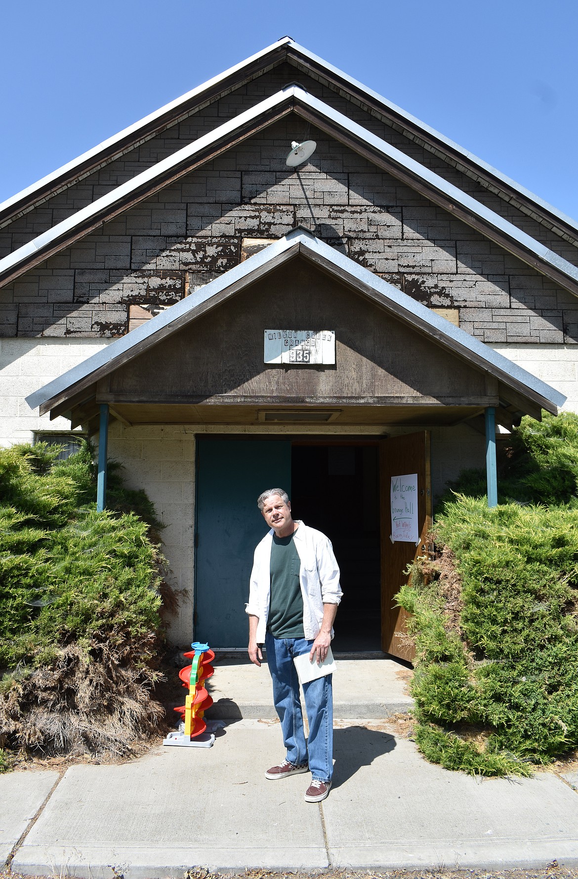 Michael Borella stands outside the former Wilson Creek Grange building, which he bought in April. He was giving away toy cars to children at the Little Big Show Saturday.