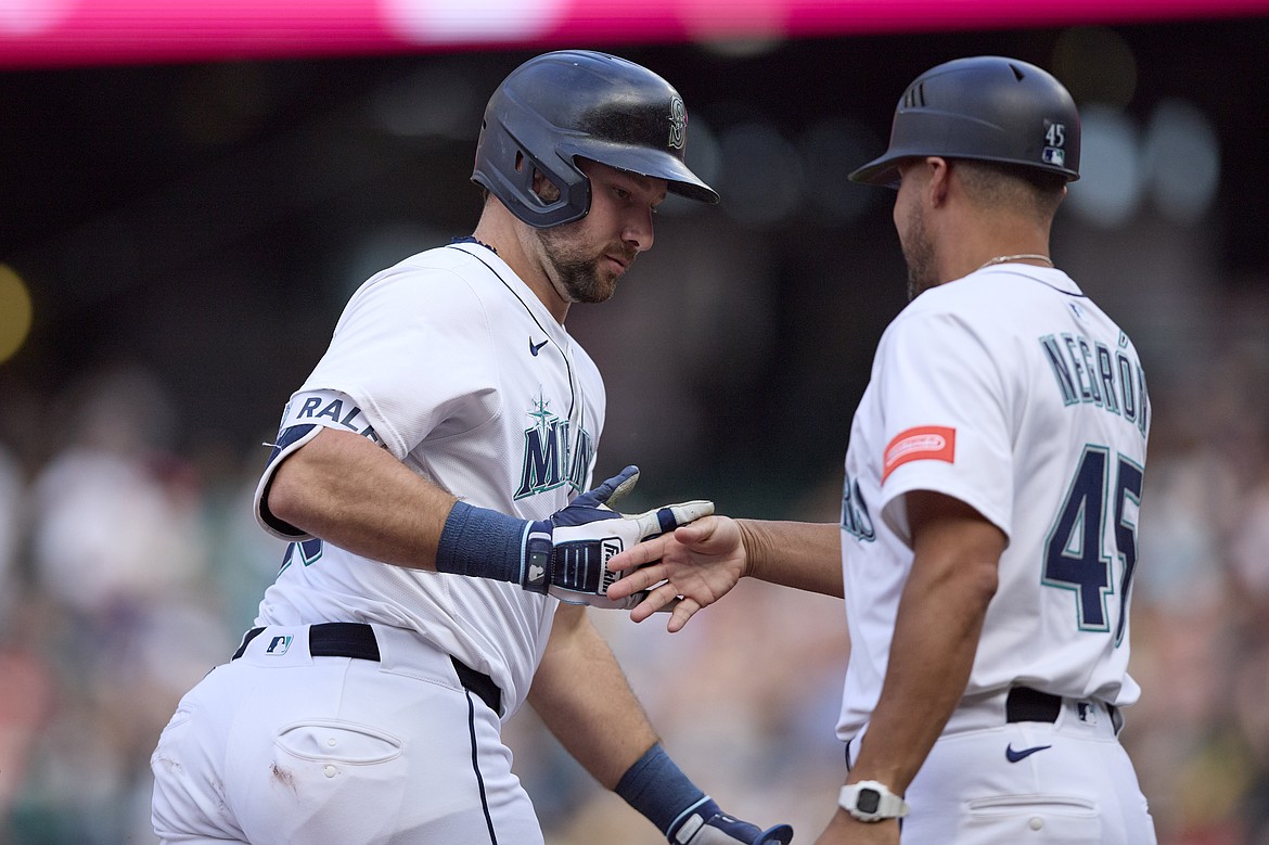 Seattle Mariners' Cal Raleigh is greeted by third base coach Kristopher Negrón on a grand slam off Boston Red Sox starting pitcher Walker Buehler during the second inning of a baseball game, Tuesday, June 17, 2025, in Seattle.