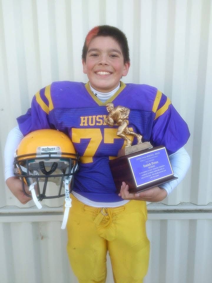 A young Isaiah Perez from his youth football days posing with his helmet and the Steve Page Memorial Award he earned. Perez said he has been playing football since he was in third grade.