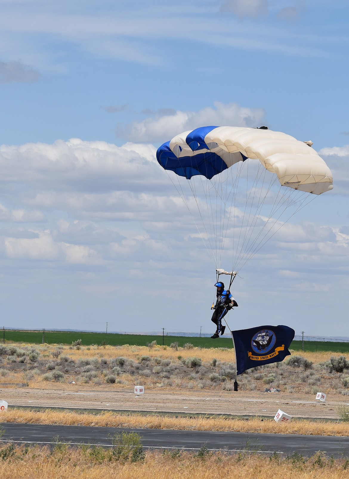Wings of Blue jumper Colin Laughrey, of Naples, Florida, comes in for a landing towing the U.S. Navy flag at the Moses Lake Airshow. Laughrey has made 698 jumps, according to the Wings of Blue announcer.