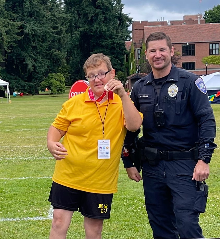 Brandon Svopa stands with an officer and holds up his bronze medal after the bocce state tournament. Bocce is still a relatively new sport in the Special Olympics with this being the fifth year since its addition, said coach Shane Lunderville.