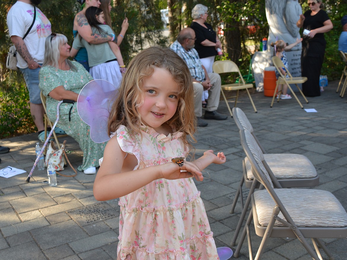 Bailey Turningrobe smiles at a butterfly that landed on her during the community memorial butterfly release Tuesday in the Share Hope Garden in Coeur d'Alene.