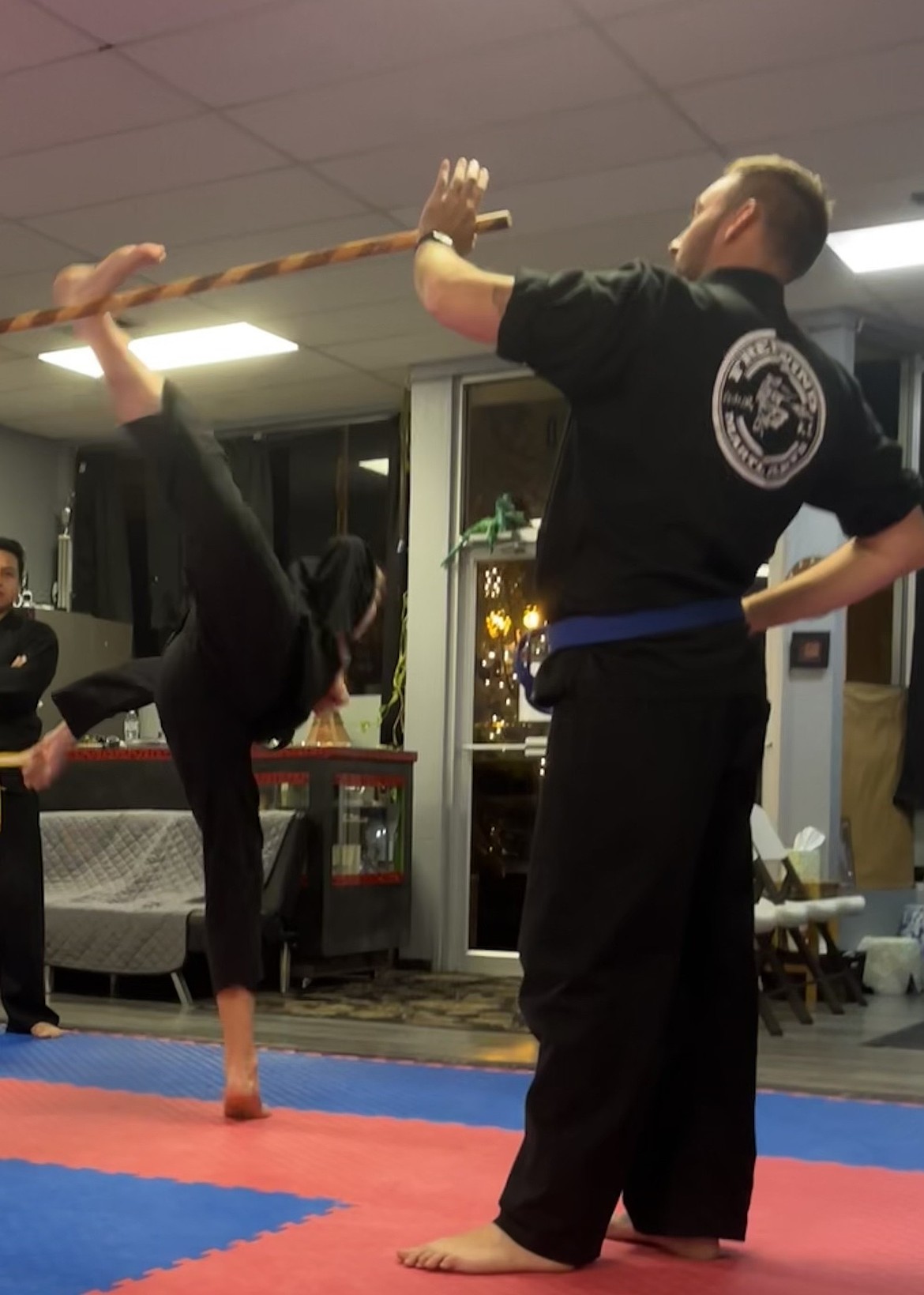 Matthias Kalmbach kicking over a staff in the Freewind Martial Arts studio. Kalmbach is a green with white belt and helps instruct while at the studio. It’s a responsibility most students take on as they rank up.