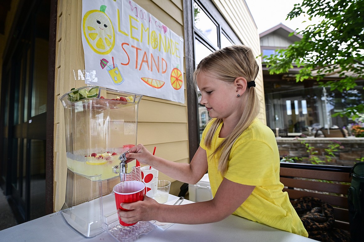 Aleia serves a cup of her lemonade at her stand named Aleia's Lemonade for Lemonade Day on Saturday, June 28. (Casey Kreider/Daily Inter Lake)
