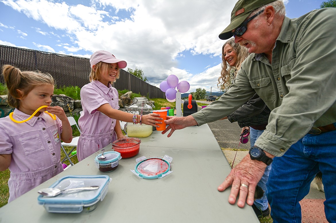 Arya, left, and Emmy Kuhlin serve a cup of lemonade to Brian and Kathy Nelson at their Pink Lemonade Express stand for Lemonade Day on Saturday, June 28. (Casey Kreider/Daily Inter Lake)