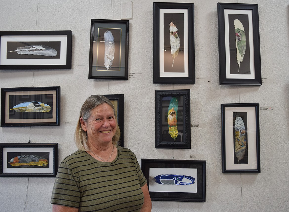 Leanne Hickman, co-owner of the Up Town Art Gallery, stands near her painted peacock feathers.