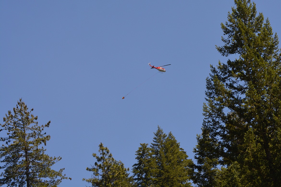 A helicopter with a bucket flies over Nettleton Gulch Road after dropping water onto the Nettleton Gulch fire on Canfield Mountain.