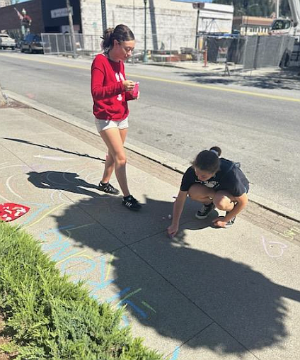 Sisters Thalia Tavis, 18, left, and Emma Thalia, 16, contribute messages of encouragement to a sidewalk chalk area Monday afternoon on Lakeside Avenue.