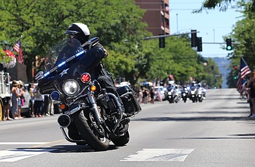 A motorcycle officer turns the corner on Sherman Avenue as the procession heads up Fourth Street.
