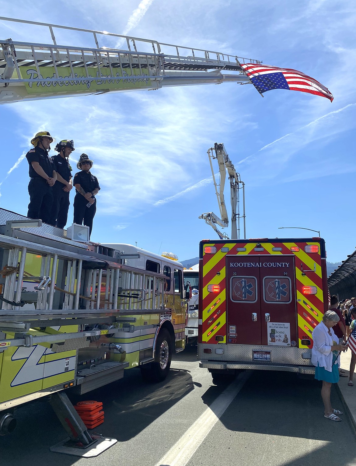 Firefighters stand on top of a truck as the flag flies high.
