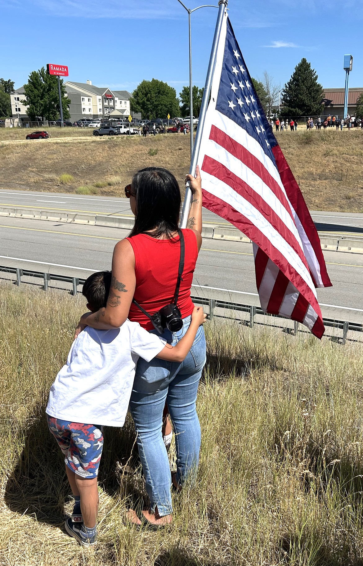 Ashley Reagan, joined by children Richie and Raelyn, wait the arrival of the procession from Spokane to Coeur d'Alene for two fallen firefighters near the Fourth Street Bridge on Tuesday.