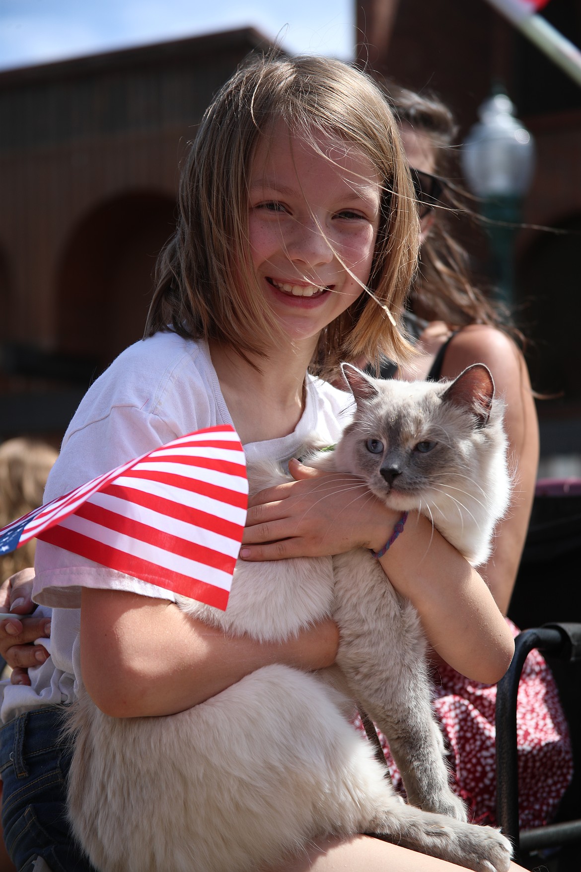 A young 4-H'er holds her cat as they ride on a float during Friday's Fourth of July grand parade.