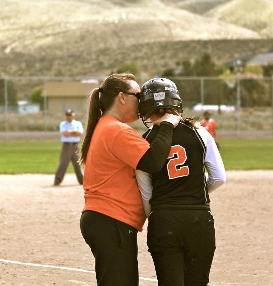Tigers’ head coach Heather Wood talks to one of her players as they prepare to go up to bat. Wood plans to support the softball team even after her retirement.