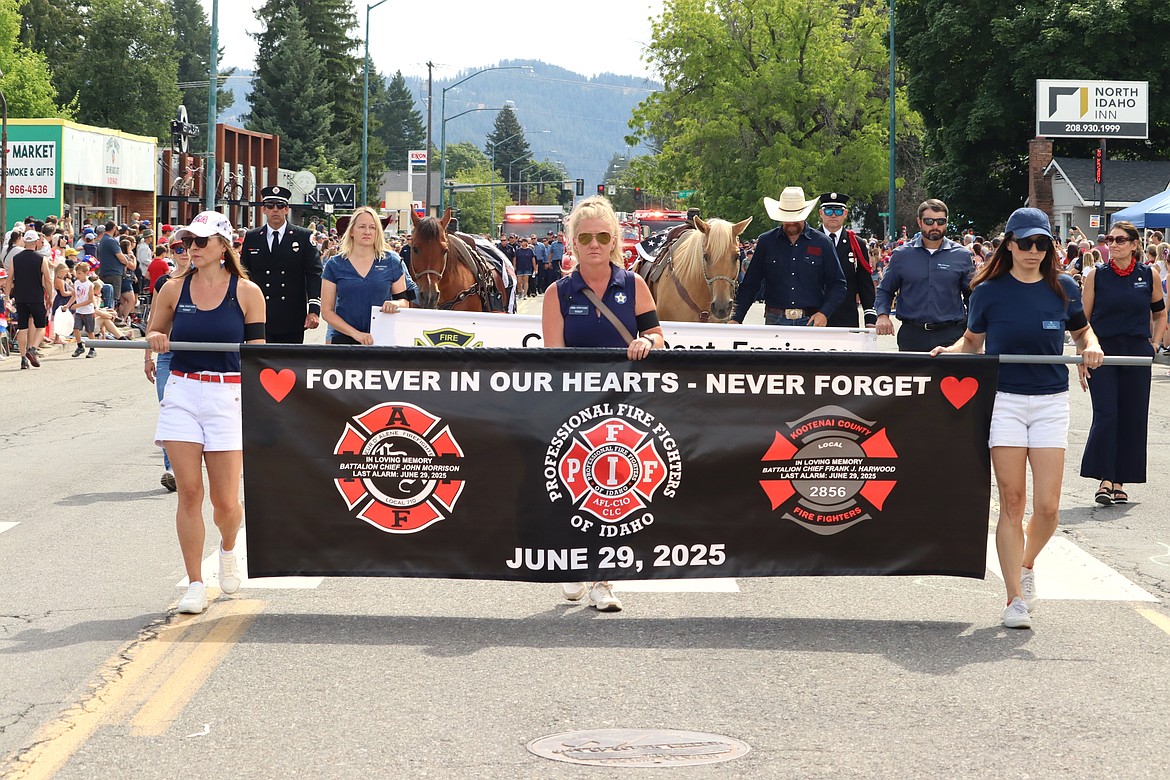 A banner bearing the names of John Morrison and Frank Harwood is carried in the Fourth of July parade on Friday.