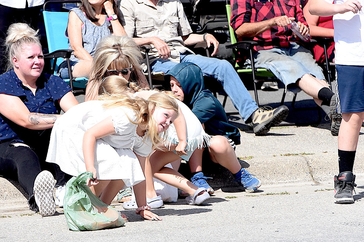 A young candy collector picks up a sweet treat while keeping her eye open for more at Friday's 2025 Troy July 4 parade. (Scott Shindledecker/The Western News)
