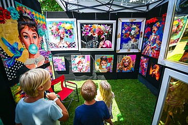 Visitors check out the oil and acrylic urban contemporary pieces of artist Oriana Gerez, owner of Gerez Gallery in Miami, Florida, at the Glacier Art Museum's 55th annual Arts in the Park festival in Depot Park in Kalispell on Friday, July 18. Kalispell's longest-running arts and music festival features a lineup of 80 juried artist booths, plein air painters, live music, food trucks and a beer and wine garden. (Casey Kreider/Daily Inter Lake)