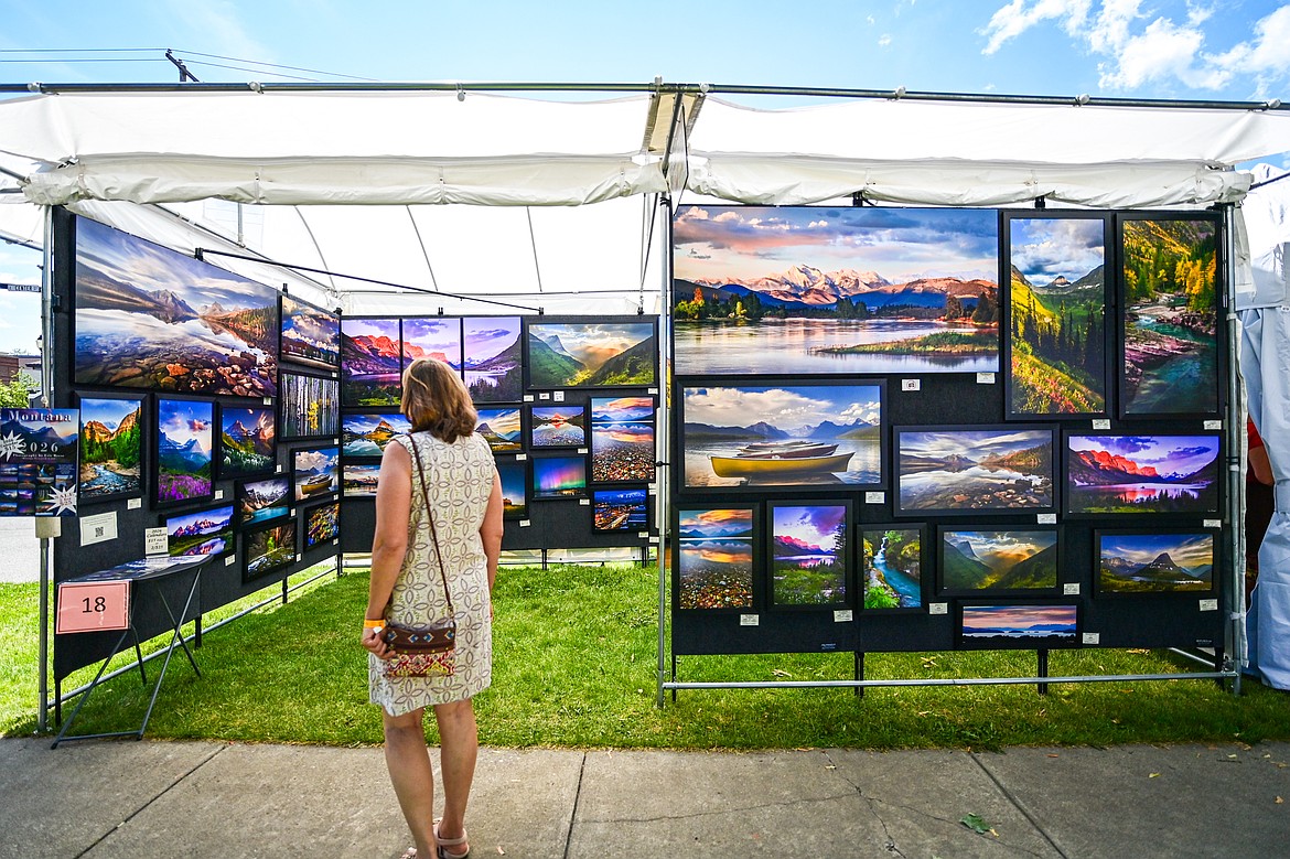 Visitors looks over the work of fine art photographer Eric Reese, of Whitefish, at the Glacier Art Museum's 55th annual Arts in the Park festival in Depot Park in Kalispell on Friday, July 18. Kalispell's longest-running arts and music festival features a lineup of 80 juried artist booths, plein air painters, live music, food trucks and a beer and wine garden. (Casey Kreider/Daily Inter Lake)