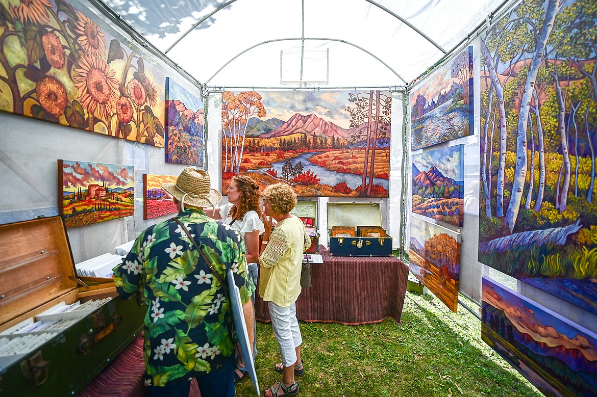 Visitors look over the work of fine artist Maia Leisz from Sagle, Idaho at the Arts in the Park festival in Depot Park in Kalispell on Friday, July 18. Kalispell's longest-running arts and music festival features a lineup of 80 juried artist booths, plein air painters, live music, food trucks and a beer and wine garden. (Casey Kreider/Daily Inter Lake)