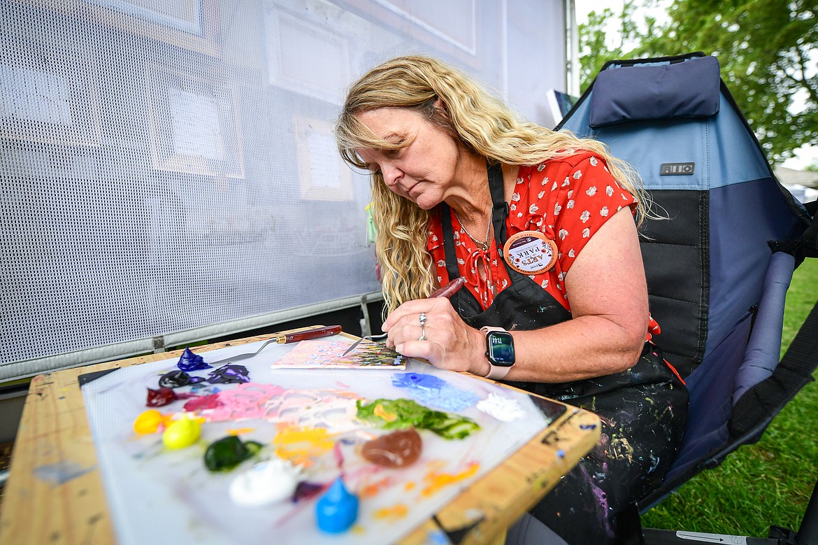 Artist Raette Meredith, owner of the Tipsy Brush studio in Kila, uses a palette knife to create a small oil painting outside her booth at Glacier Art Museum's 55th annual Arts in the Park festival in Depot Park in Kalispell on Friday, July 18. Kalispell's longest-running arts and music festival features a lineup of 80 juried artist booths, plein air painters, live music, food trucks and a beer and wine garden. (Casey Kreider/Daily Inter Lake)